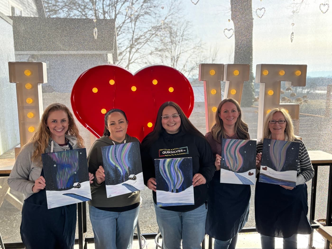 An Uplift Teams painting session, participants holding their finished canvases